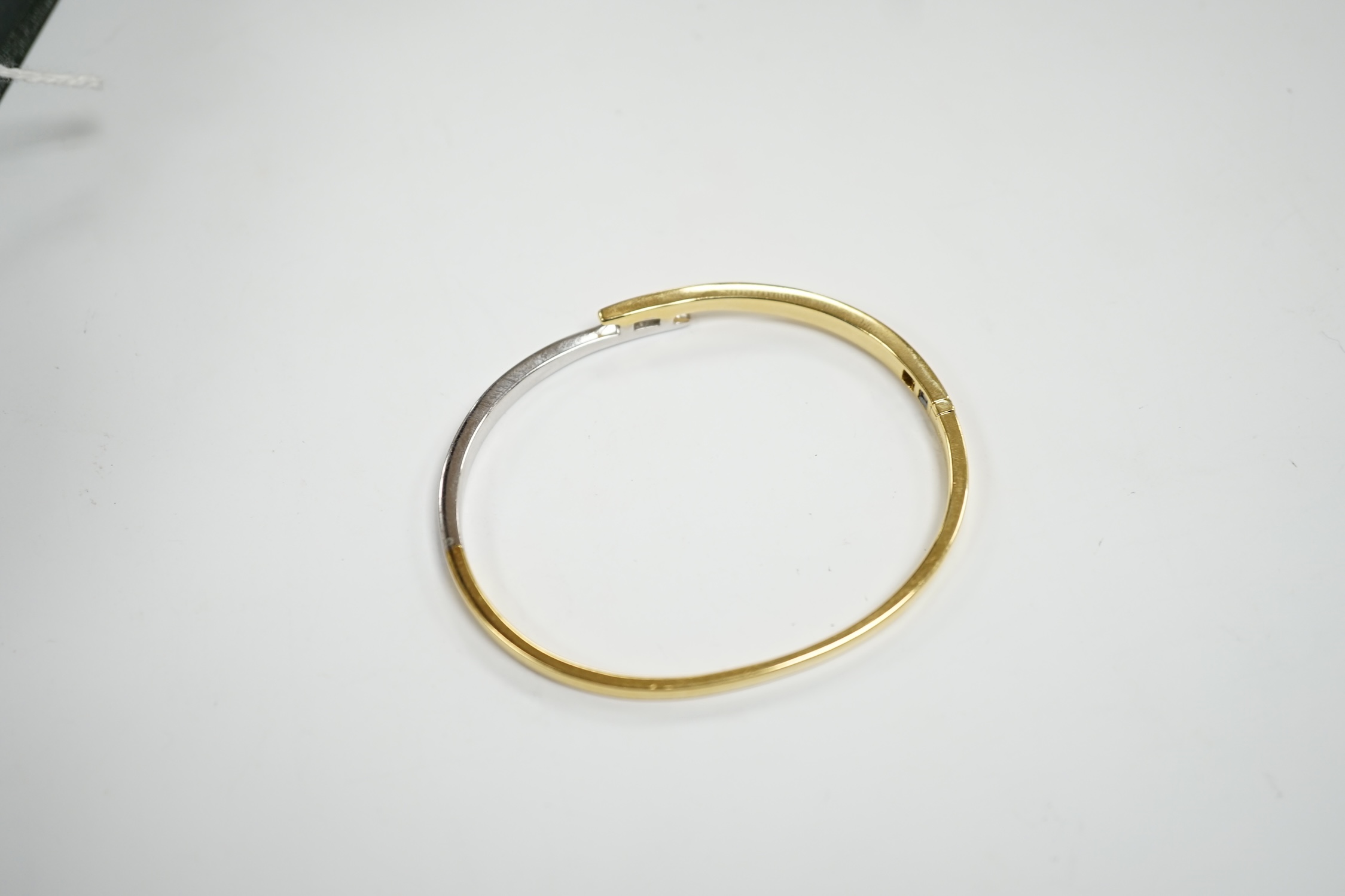A modern two colour 18k and three stone princess cut diamond set hinged bangle, interior 60mm, gross weight 23.4 grams.